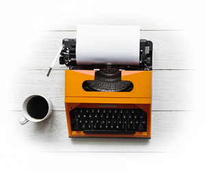 Orangefarbene Schreibmaschine, daneben eine Kaffeetasse