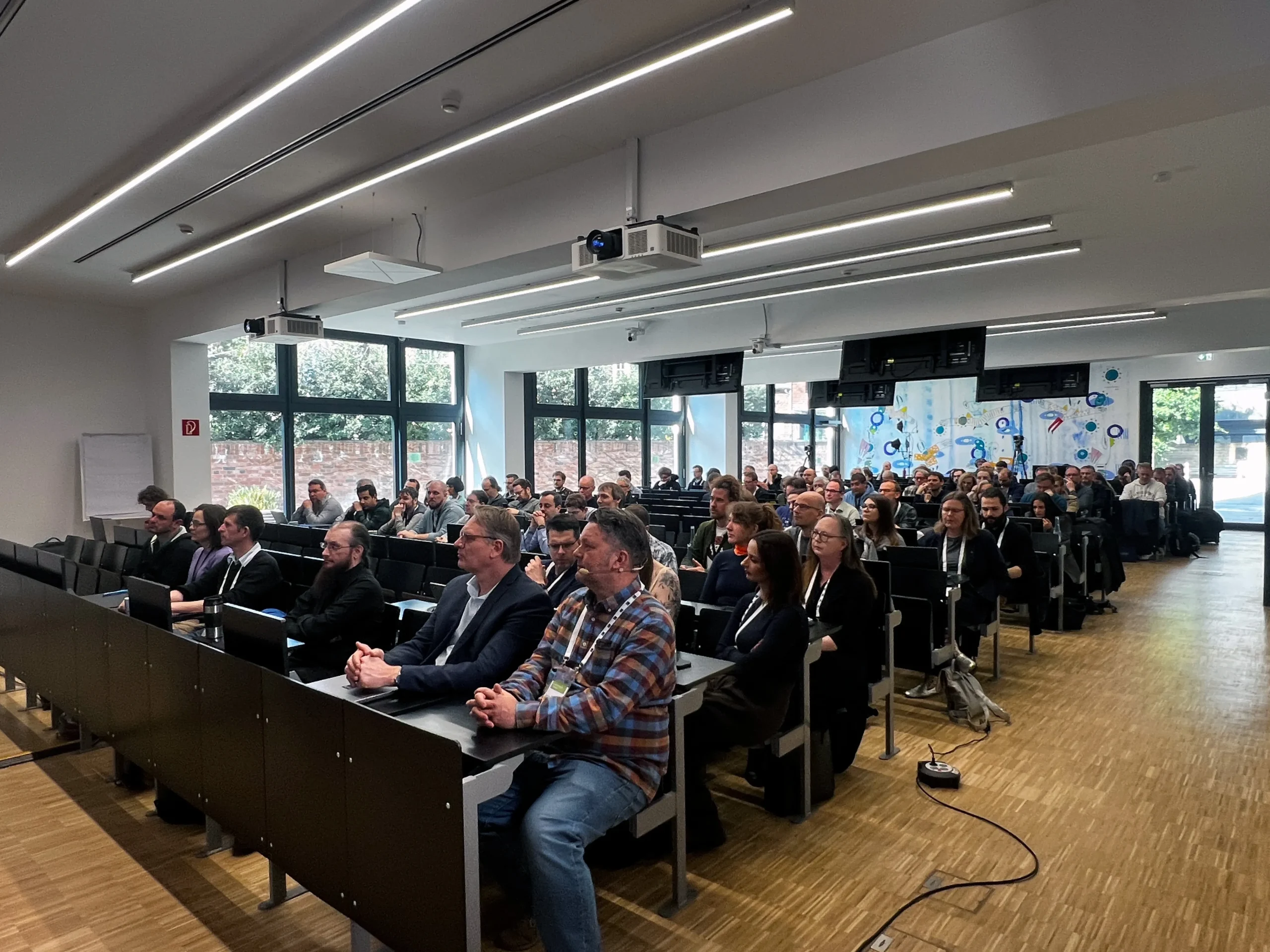 Foto: Vortragsraum mit Publikum, schräg von vorne aufgenommen.