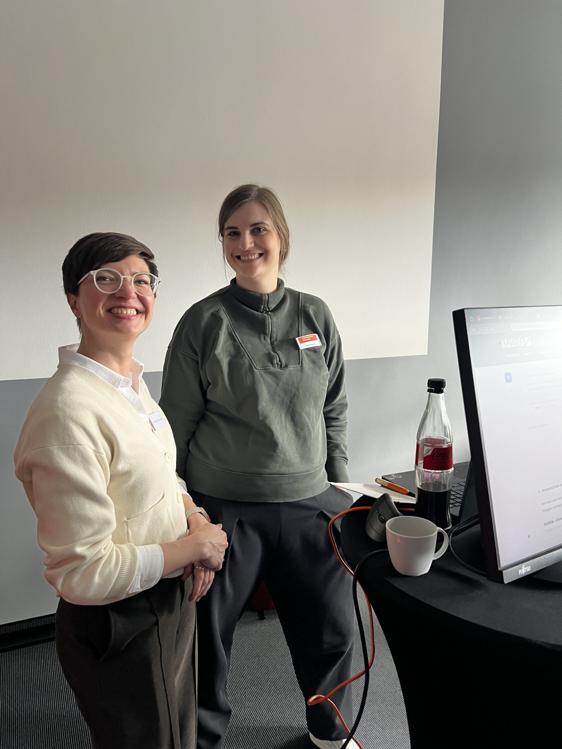 Foto: Johanna Munkelt und Eva Schameitat stehen neben einem Stehtisch mit einem Monitor