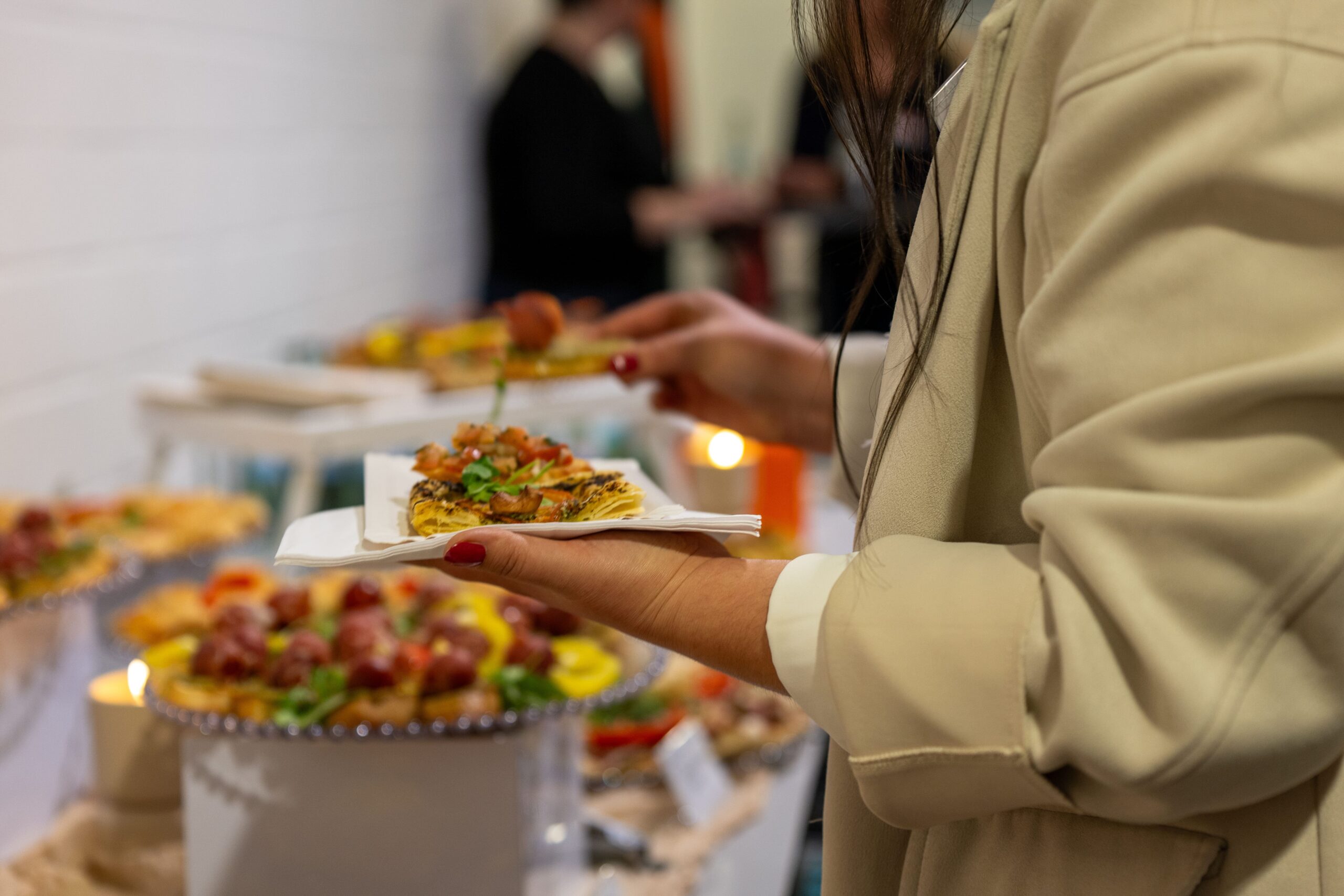 Foto: Frau in beigem Mantel bedient sich an einem Buffet